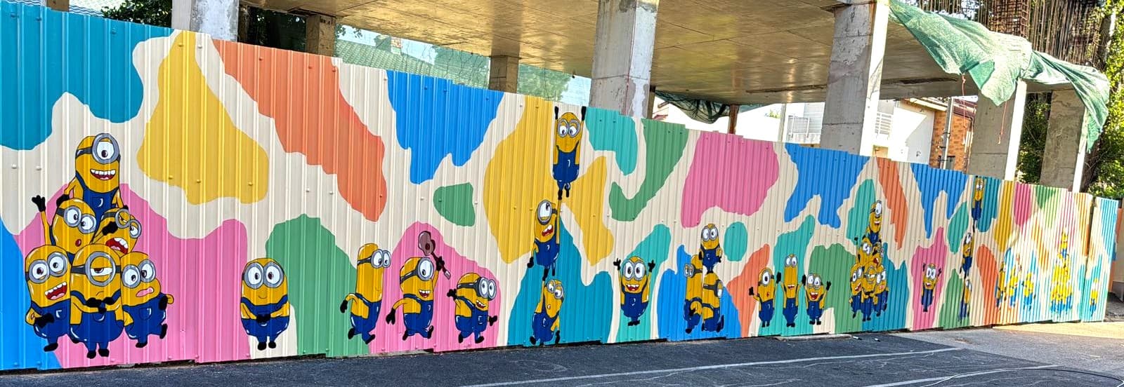 Pictură murală exterioară pentru grădiniță: personaje animate jucăușe pictate pe gard de tablă vedere din ansamblu. Lucrare realizată de ARTRA Paintings